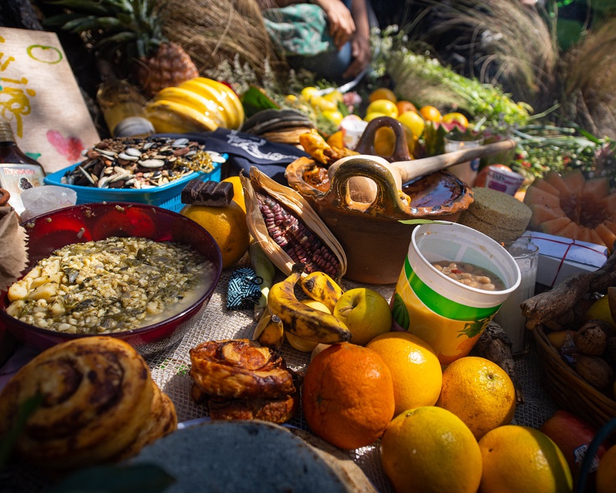 Ofrenda de comida y cruces adornadas con flores y trajes regionales