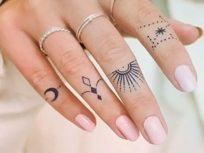 Mano de mujer con tatuajes en los dedos
