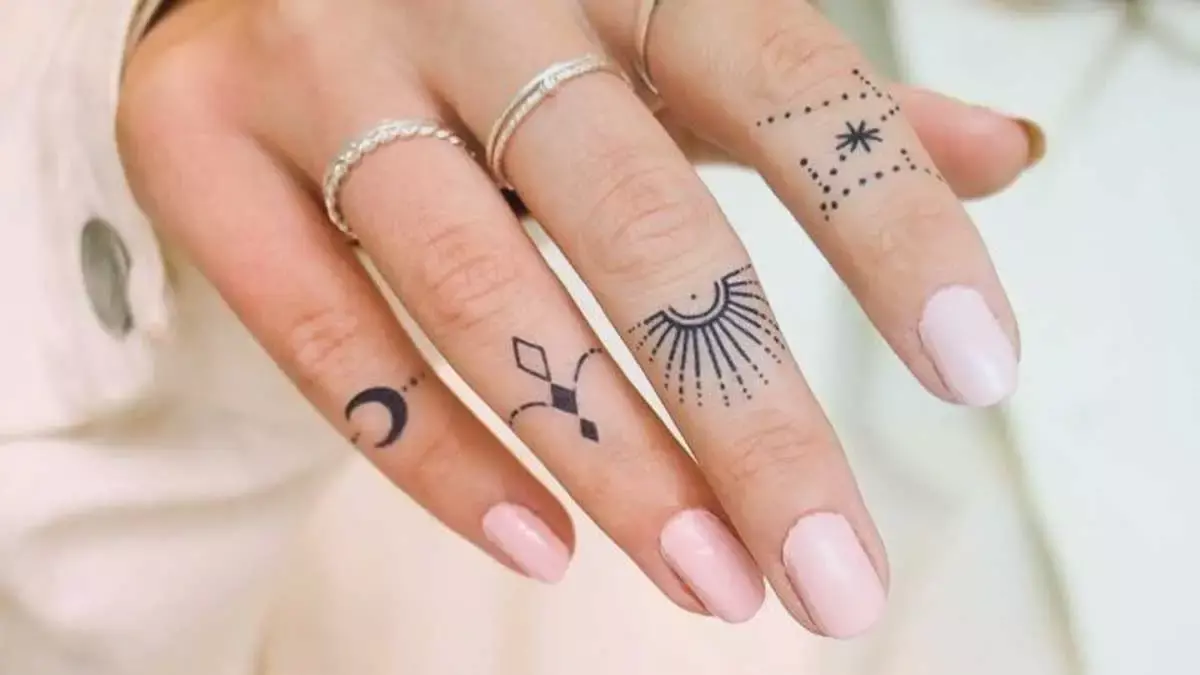 Mano de mujer con tatuajes en los dedos
