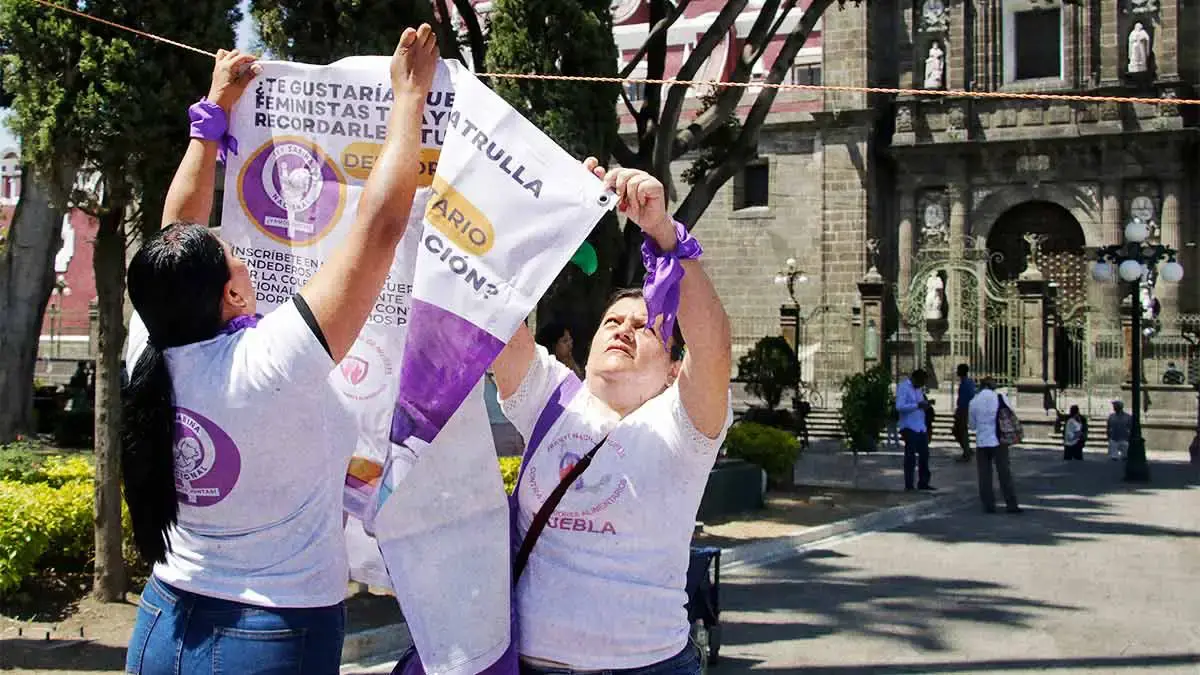 Mujeres colocan tendedero de deudores alimentarios en el Zócalo de Puebla.